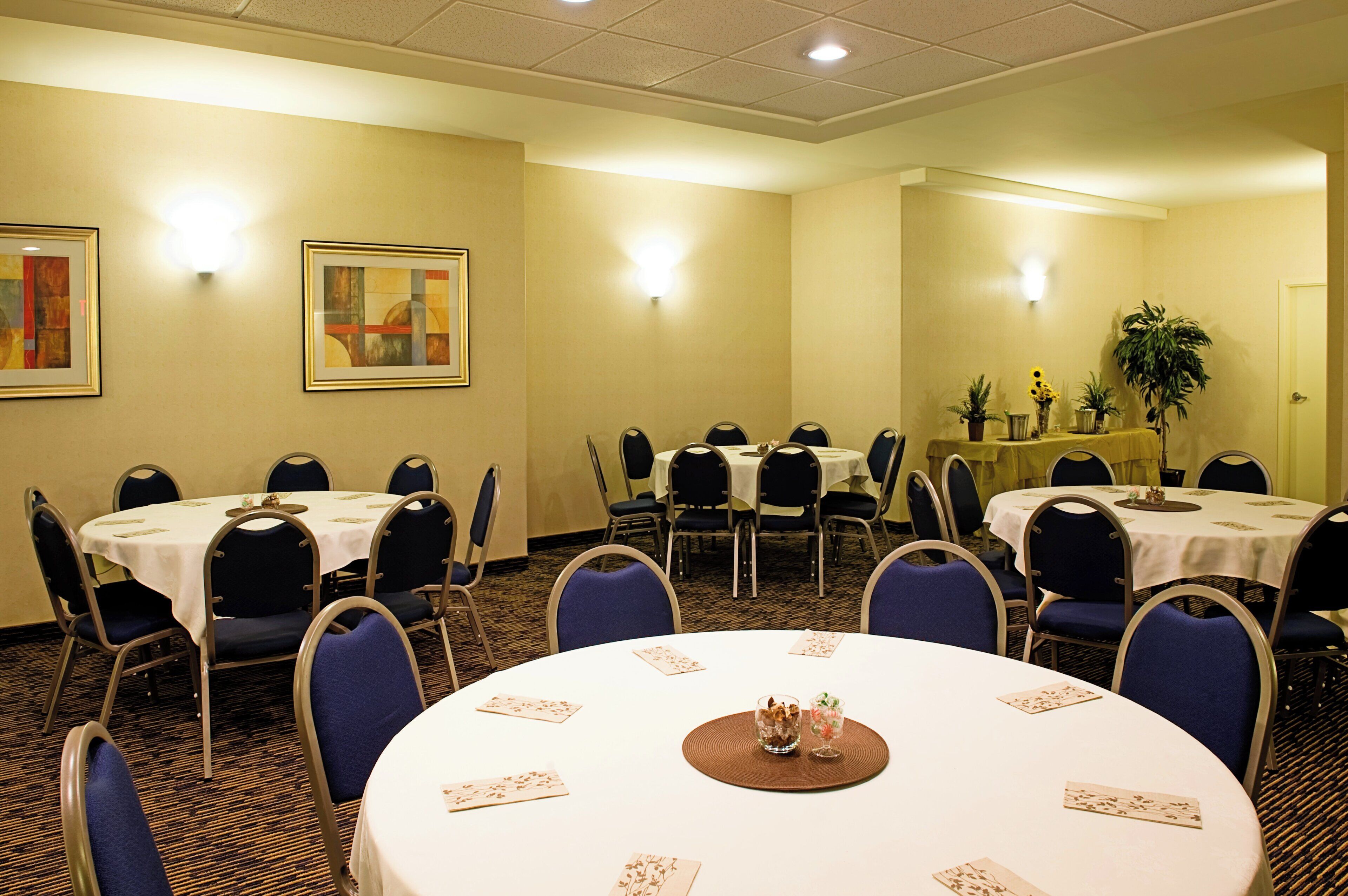 A conference room with round tables, chairs, and a painting on the wall.