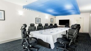 A conference room with a long table, multiple chairs, a flat-screen TV, and framed artwork on the walls. - Holiday Inn Express & Suites Regina-South by IHG (Regina)