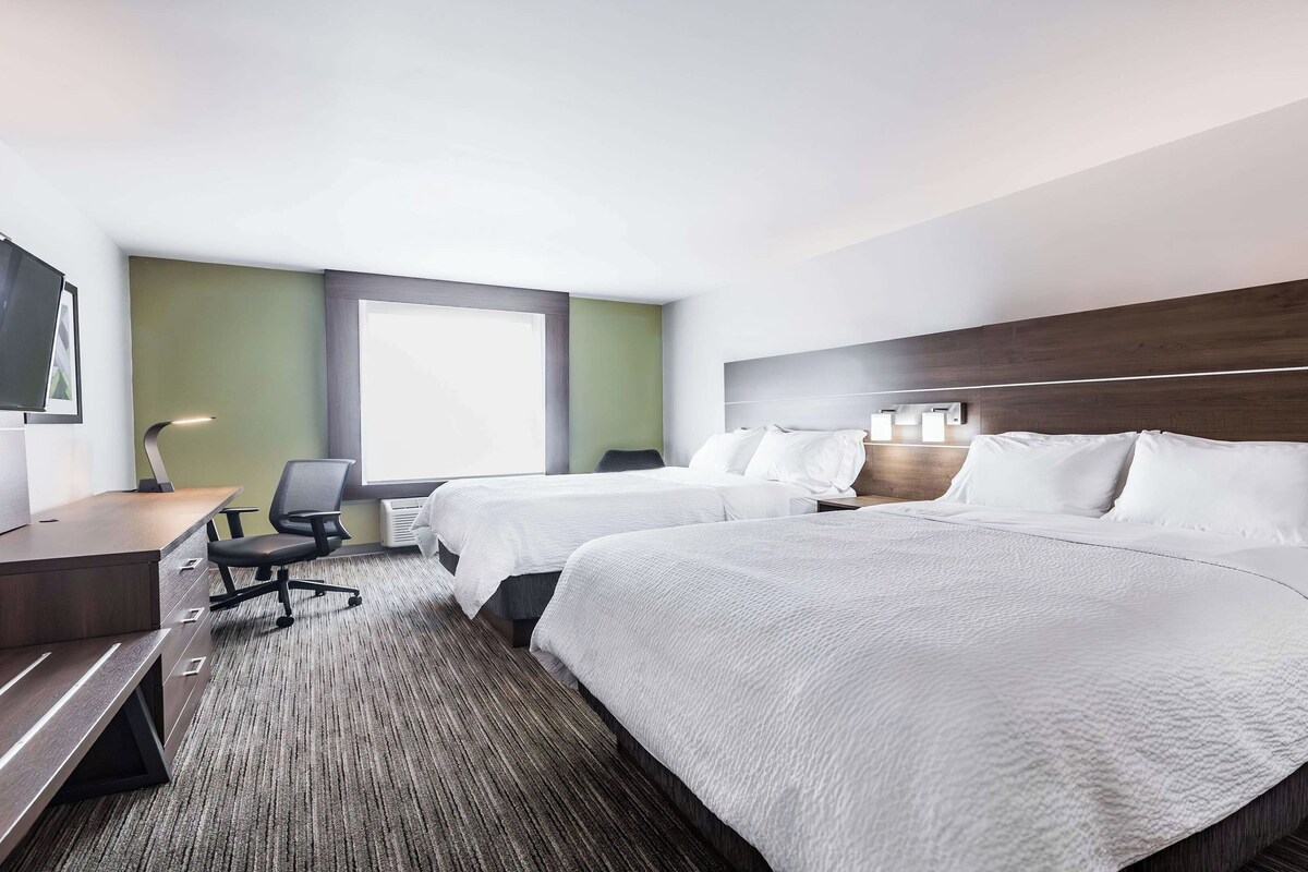 A hotel room with two beds, a desk, and a chair.