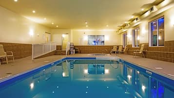 A hotel swimming pool with a tiled deck, lounge chairs, and a spa area.