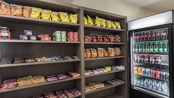 A snack and beverage display in a store, including bags of Lay's Classic and Doritos, canned drinks, and bottled water.