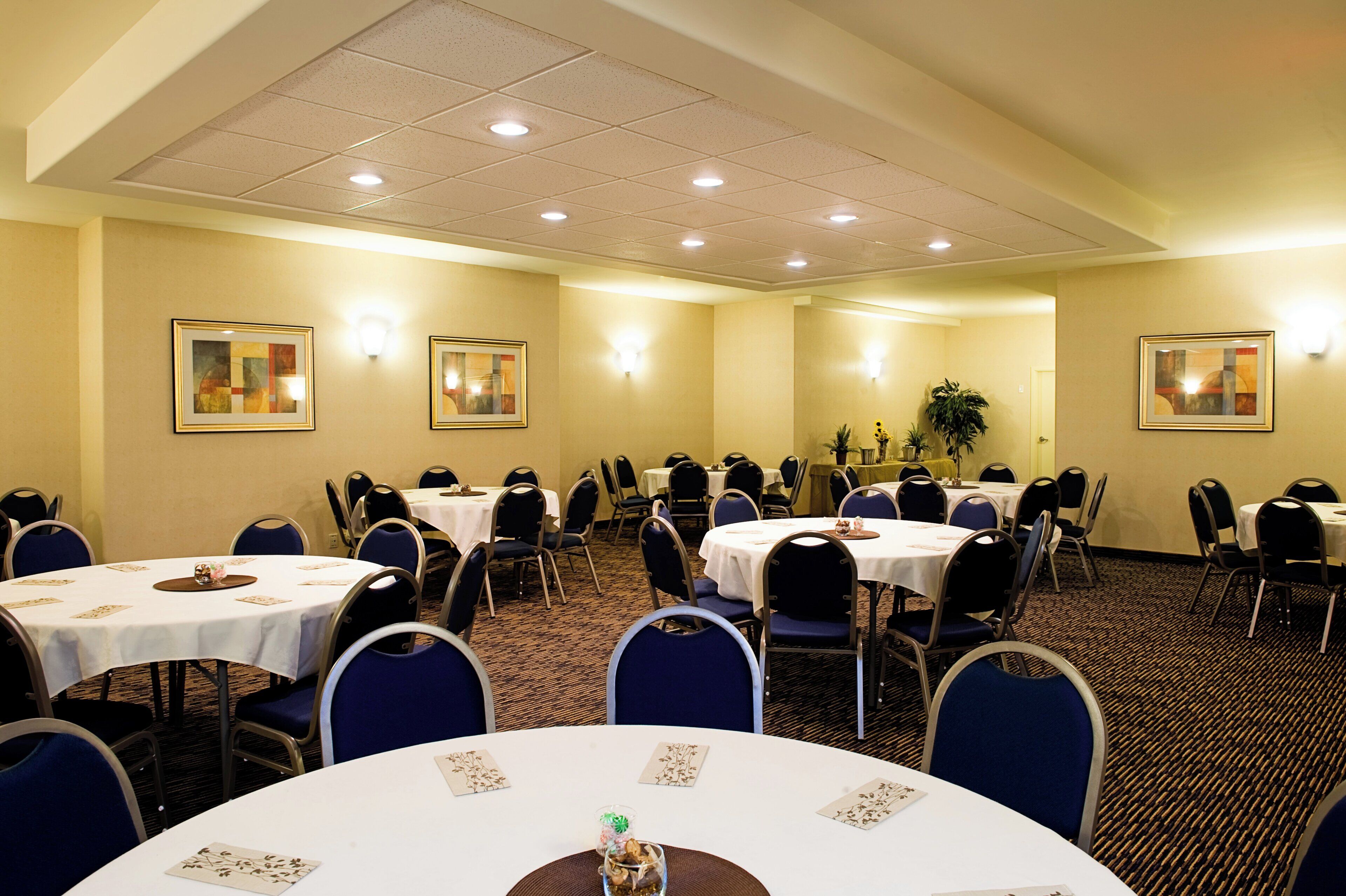A conference room with multiple tables and chairs, arranged in rows.