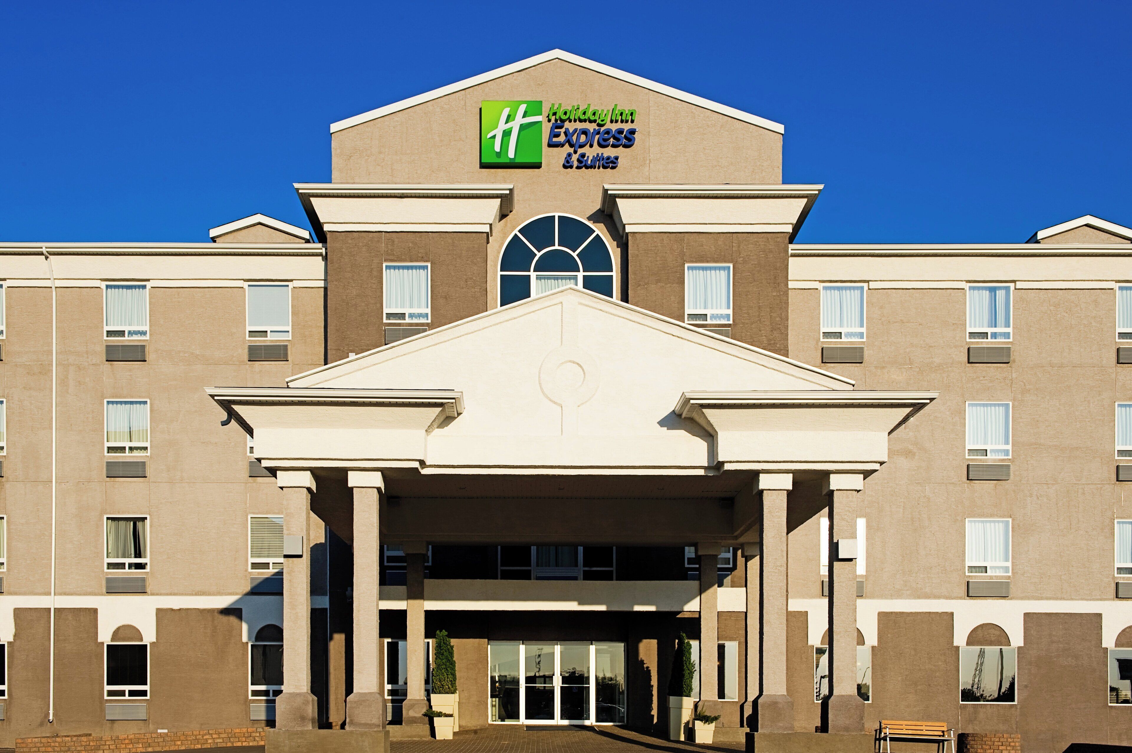 Edificio de Holiday Inn Express & Suites con fachada simétrica, ventanas amplias y una entrada central.