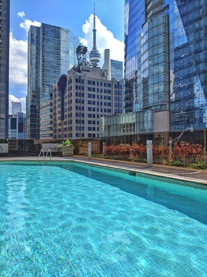 A swimming pool with a view of modern high-rise buildings, including a distinctive tower with a spire.