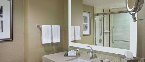 A hotel bathroom with a large mirror, a sink, a toilet, and a shower area.