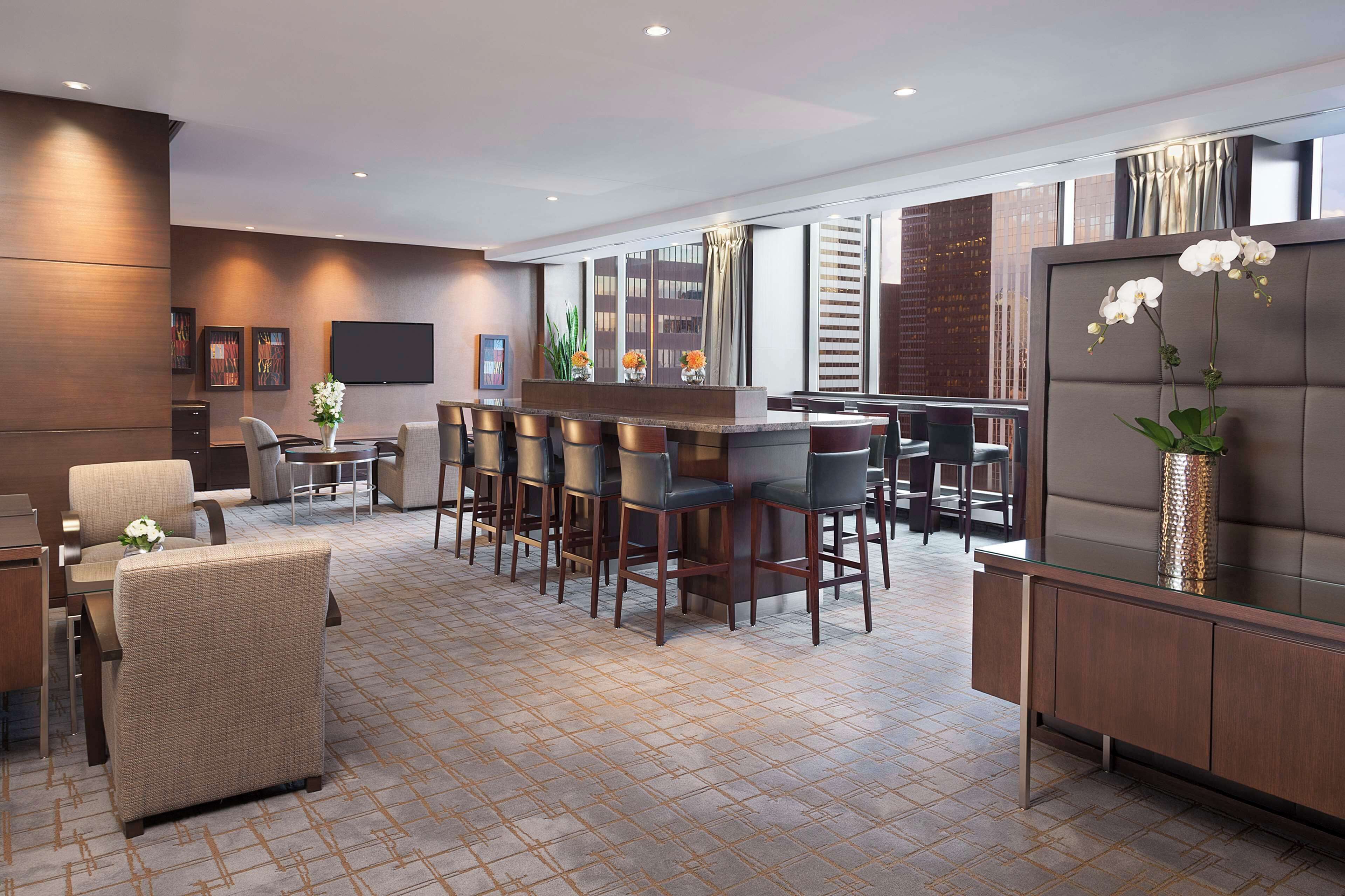 Een moderne hotellobby met een bar, zitplaatsen en een groot televisiescherm.