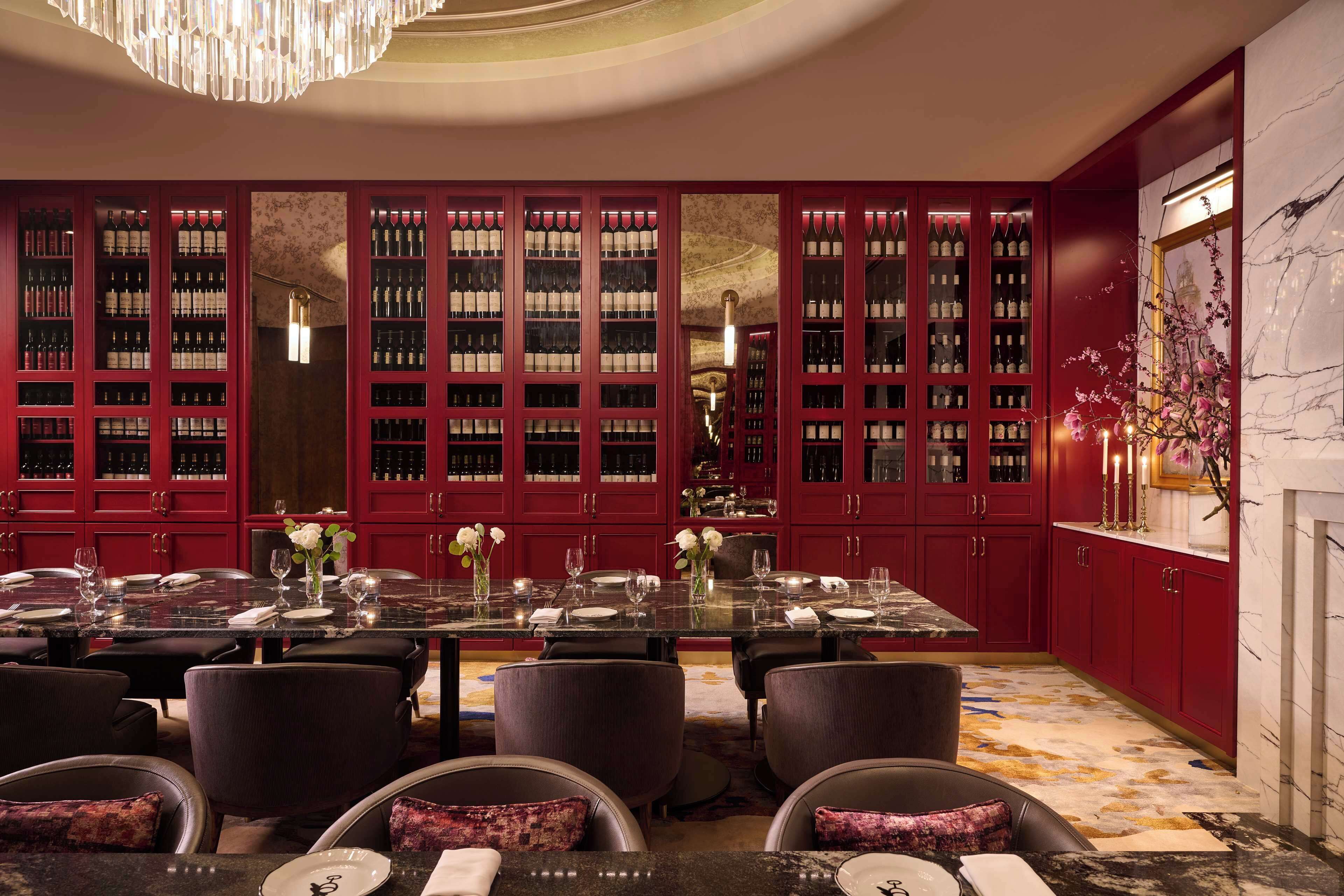 A formal dining room with a long table, red cabinets, and a marble floor.