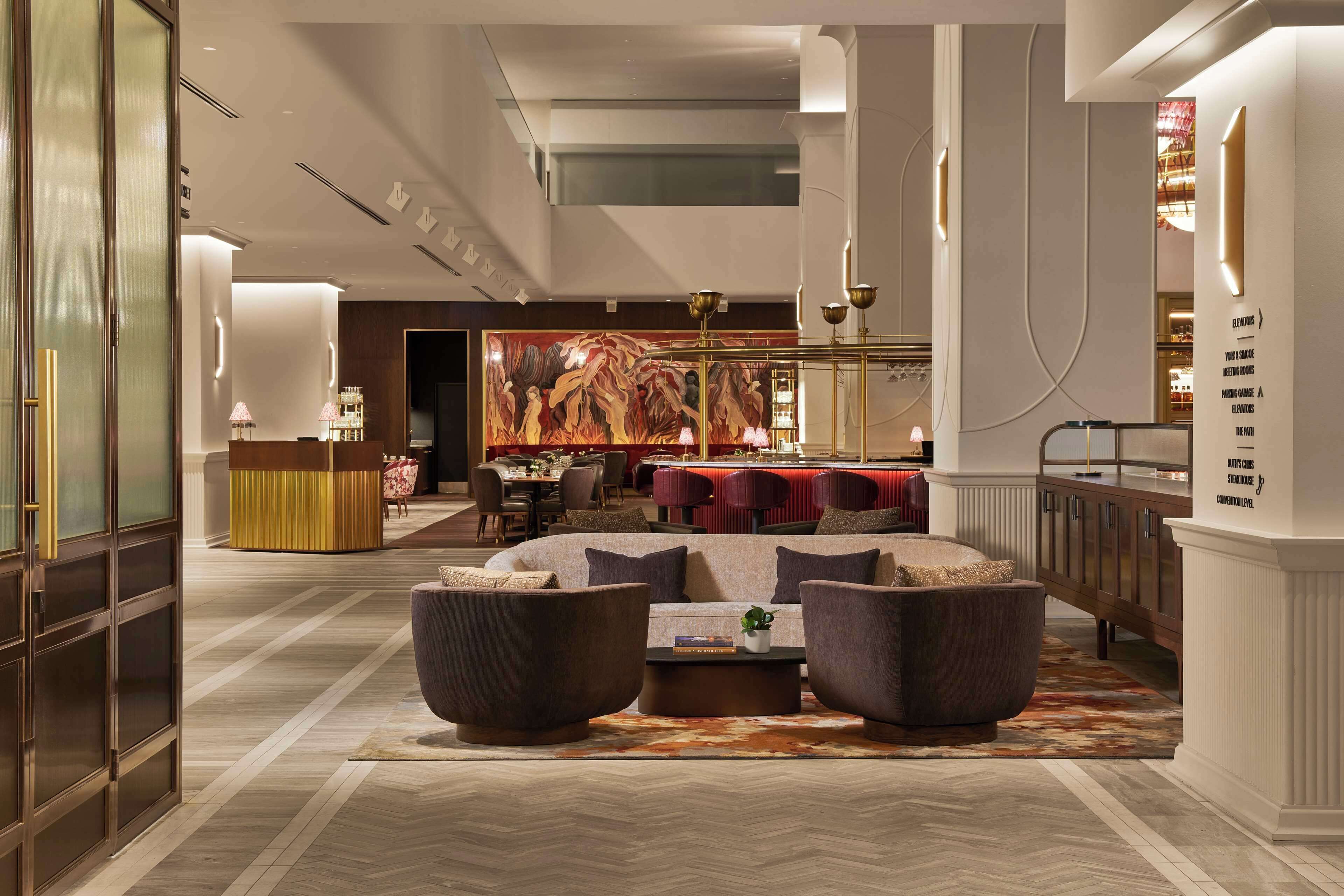 A spacious lobby with a central seating area, a reception desk, and a large mural on the back wall.