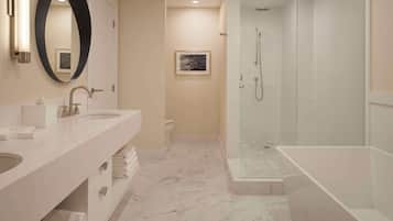 Un baño moderno con un espejo ovalado grande, dos lavamanos, un inodoro y una ducha a ras de suelo.