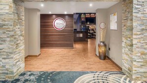 Una zona de recepción con una pared de piedra, un mostrador de madera y un jarrón grande.