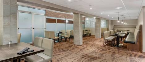 A hotel lobby with a carpeted floor, seating areas, and a reception desk.