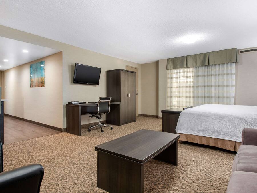 Une chambre d’hôtel équipée d’un lit, d’un bureau, d’une chaise et d’un téléviseur fixé au mur.