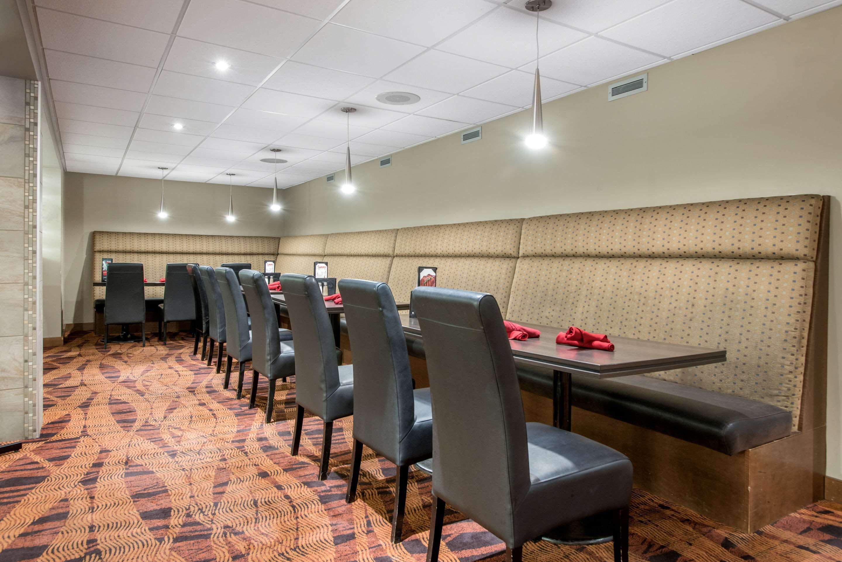 A conference room with a patterned carpet, rows of chairs, a long table, and a cushioned bench.