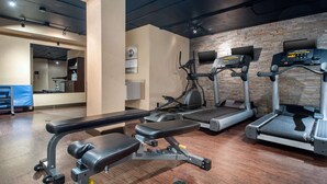 Un gimnasio con cintas de correr, elípticas y bancos de pesas.