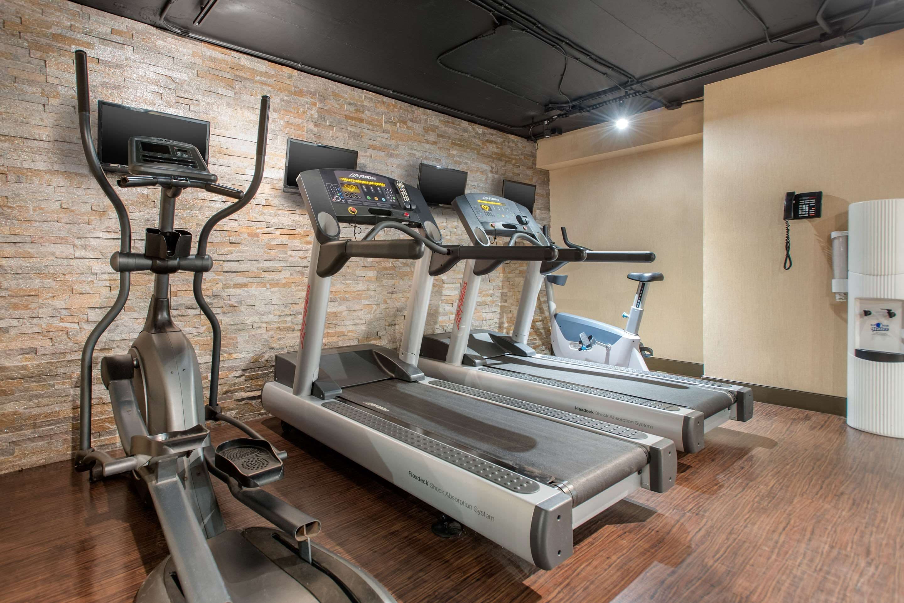 A gym with treadmills, ellipticals, and a water dispenser.