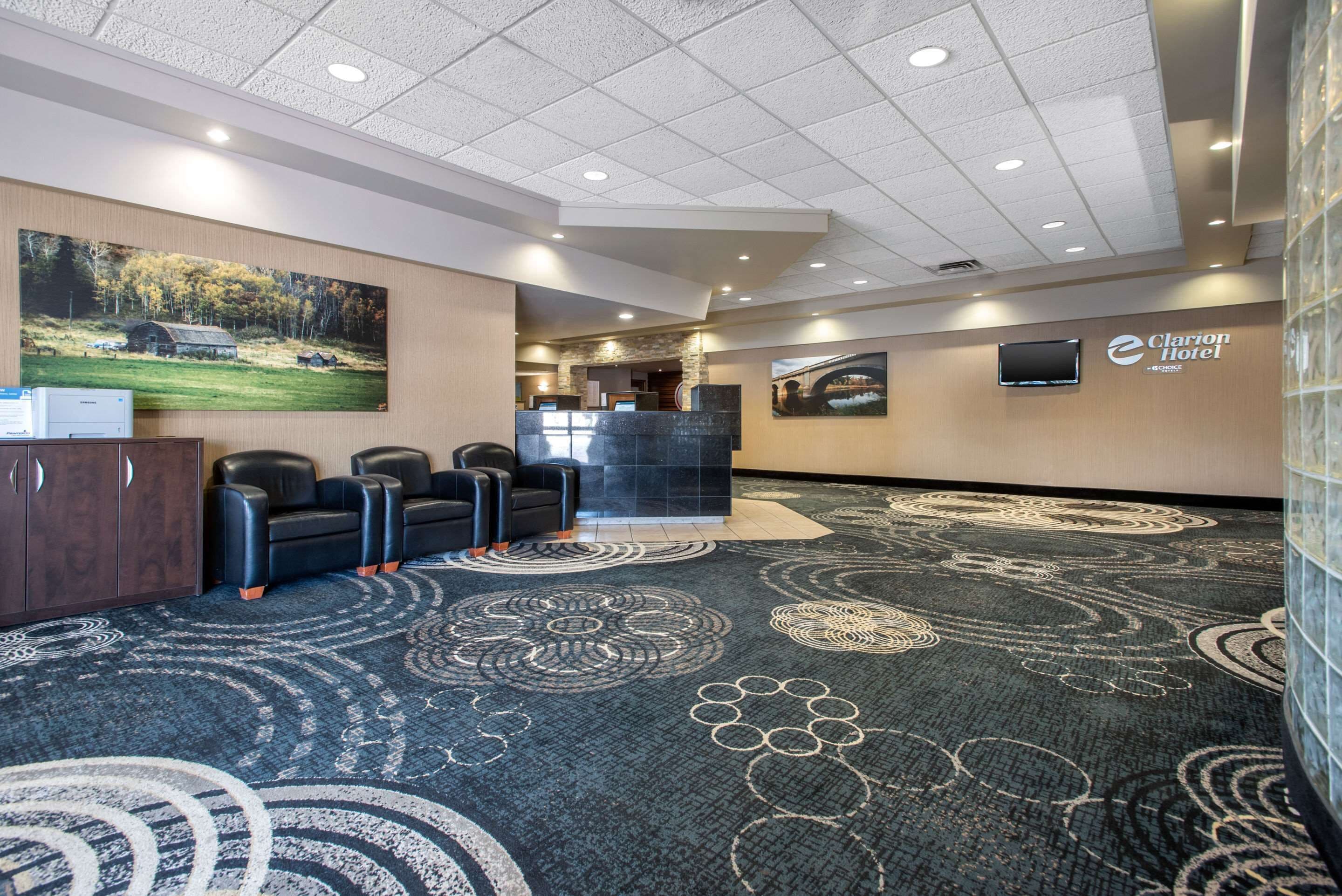 A hotel lobby with a reception desk, seating area, and artwork on the walls.