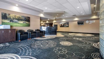 A hotel lobby with a reception desk, seating area, and artwork on the walls.