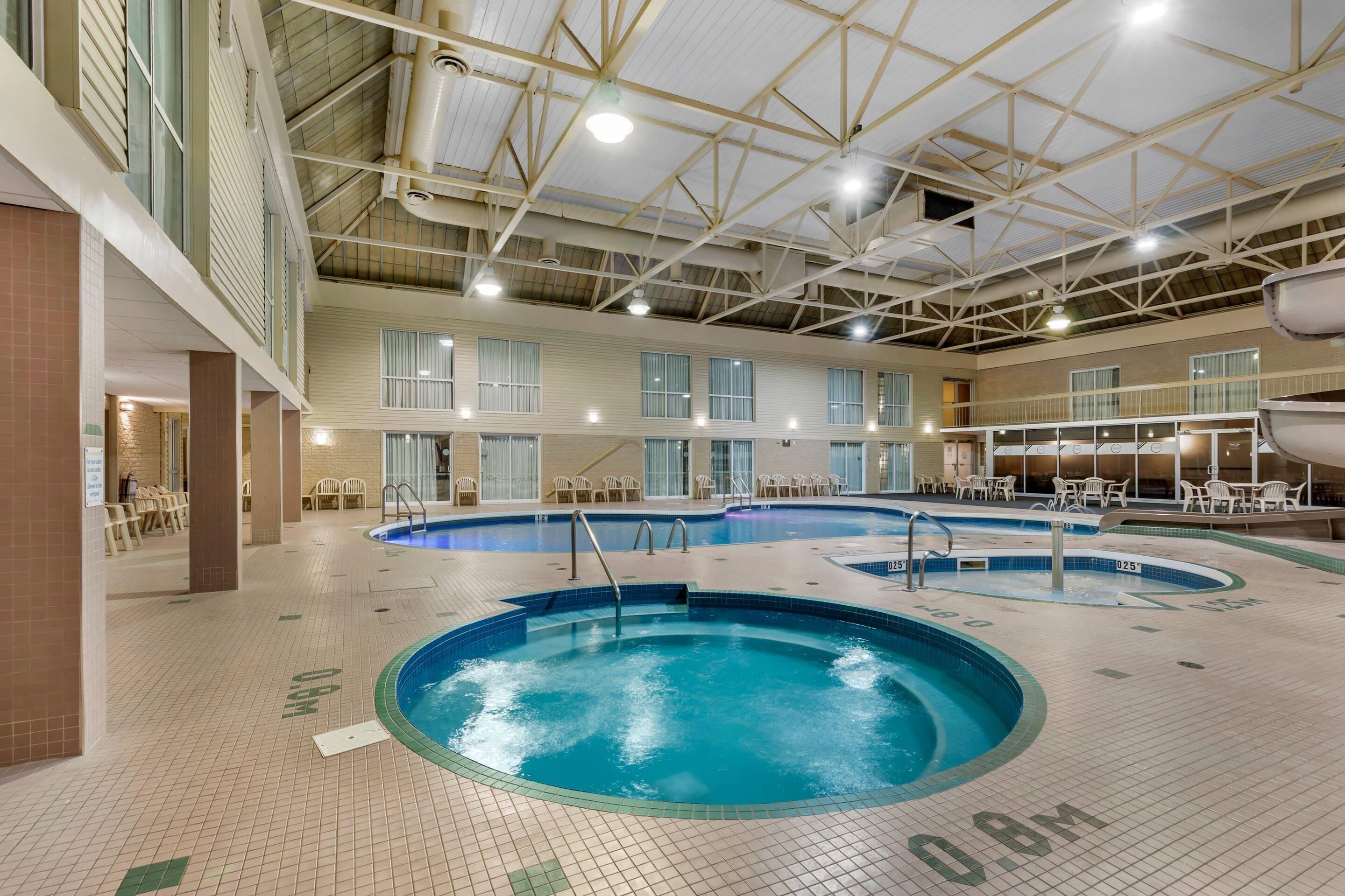 Una piscina interior con varias pistas de natación, techo alto con vigas a la vista y suelo de baldosas con flechas direccionales.