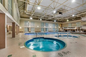 An indoor swimming pool with multiple lanes, a high ceiling with visible beams, and a tiled floor with directional arrows.