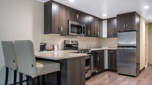 Una cocina moderna con armarios de madera oscura, electrodomésticos de acero inoxidable y encimera de color claro.
