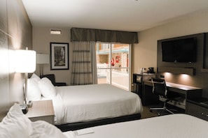 Ein Hotelzimmer mit Bett, Schreibtisch, Stuhl, Fernseher und einem Balkon mit Blick.