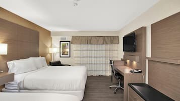 Una habitación de hotel con cama, escritorio, silla y televisión.
