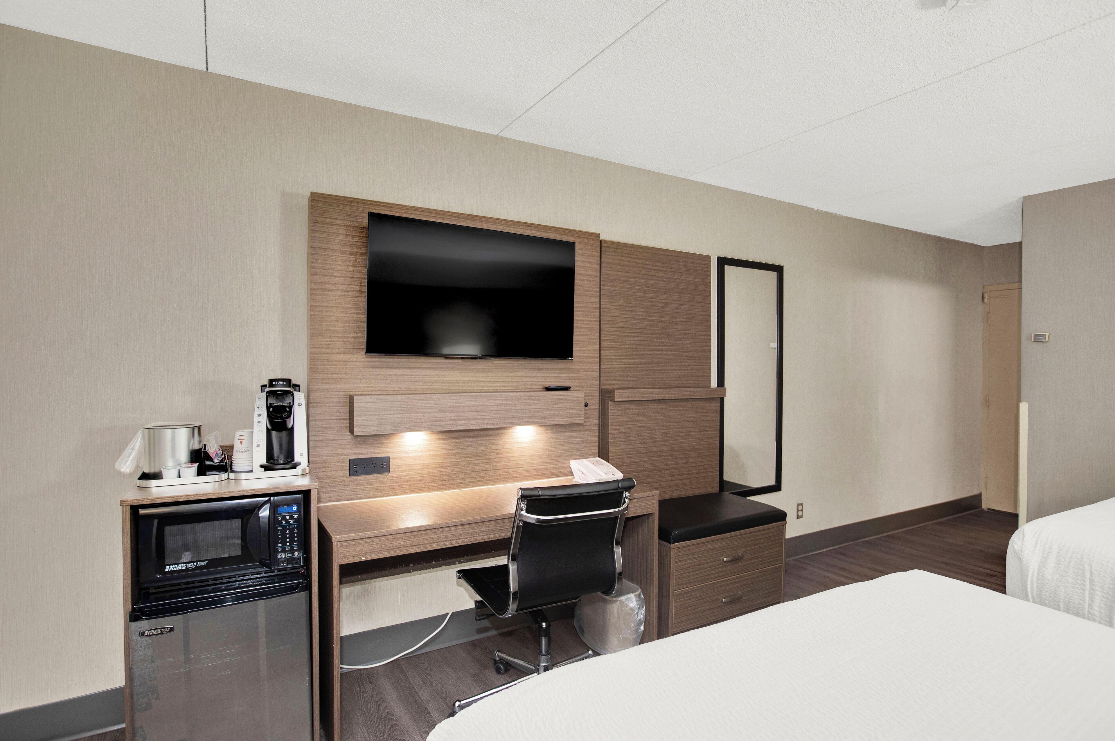 Een hotelkamer met een bed, een bureau met een magnetron, koffiezetapparaat en een televisie.