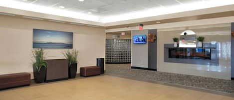 A spacious lobby with a large reception desk, seating area, and a television screen.