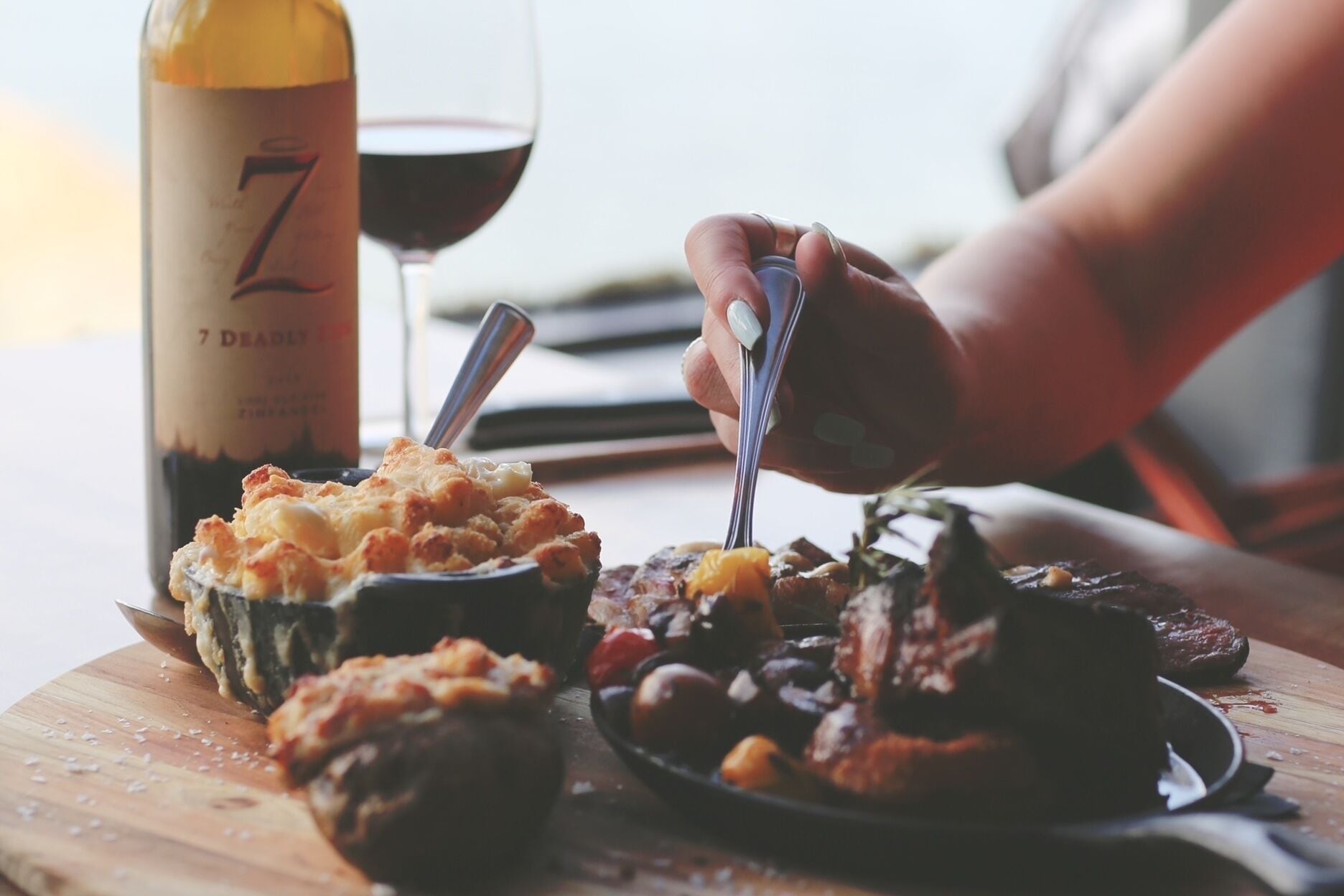 Comida con una botella de vino y una copa de vino tinto sobre una mesa.
