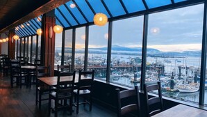 Un restaurant offrant une vue sur un port et sur le paysage urbain.