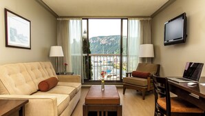 Une chambre d’hôtel équipée d’un canapé, d’un fauteuil, d’une table basse et d’un bureau avec un ordinateur portable.