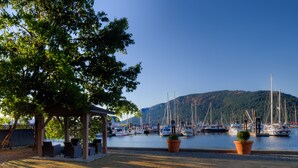 Un port de plaisance avec des bateaux amarrés, un espace de repos abrité et une montagne en arrière-plan.