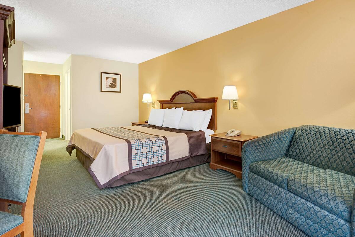 A hotel room with a bed, a sofa, a television, and a nightstand.