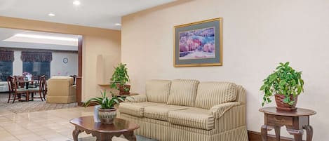A living room with a sofa, two side tables with potted plants, a coffee table, and a painting on the wall.