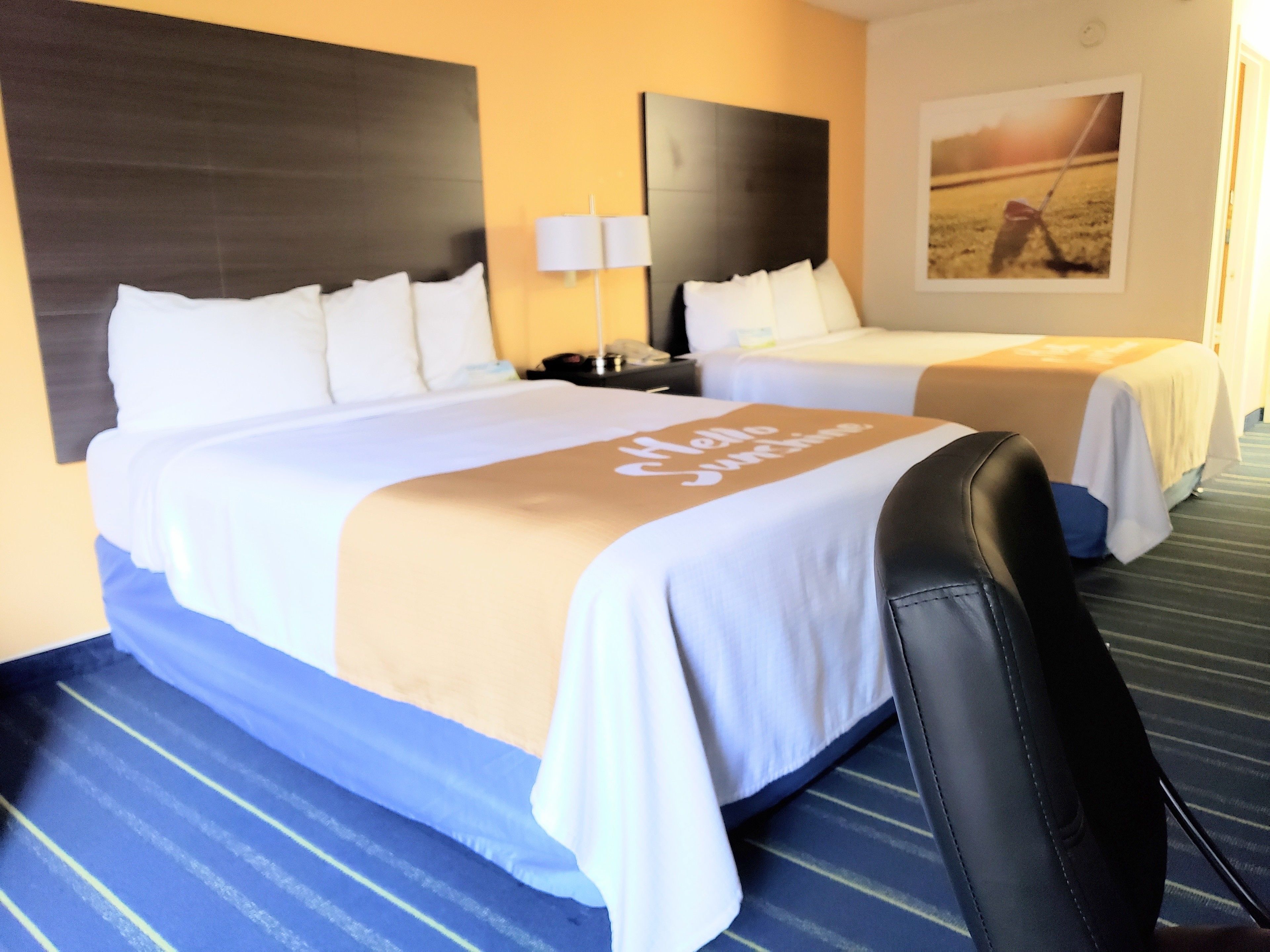 A hotel room with two beds, a desk, and a chair.
