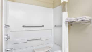 Un baño con bañera blanca, barras de apoyo, cortina de ducha y perchero.