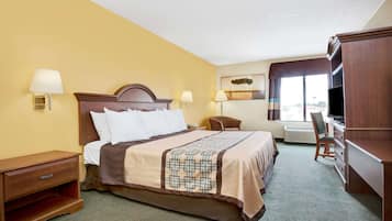 A hotel room with a bed, bedside lamps, a desk, a chair, and a television.