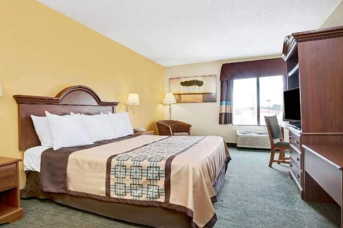 A hotel room with a bed, bedside tables, a TV, and a window.