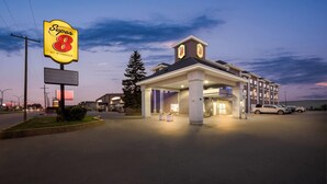 Un hotel Super 8 con un letrero llamativo, entrada cubierta y estacionamiento.