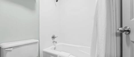 Un baño con una bañera blanca, inodoro y cortina de ducha.
