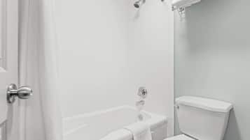 Een badkamer met bad, toilet en douche.