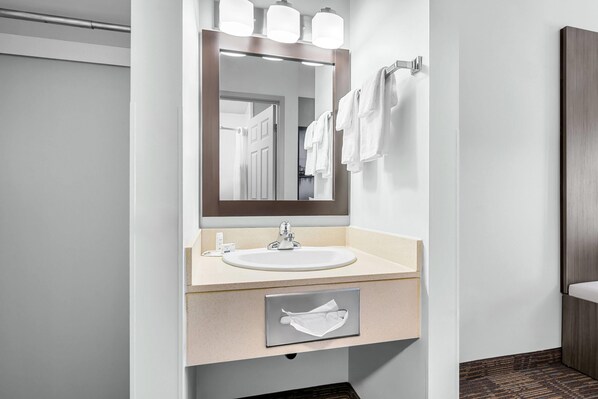 A modern bathroom with a large mirror, a sink, and a towel rack.