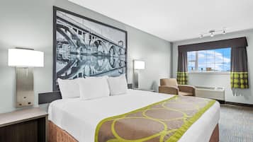 Une chambre d’hôtel avec un grand lit, deux tables de chevet, une chaise, un bureau, une grande fenêtre avec des rideaux et un climatiseur fixé au mur.
