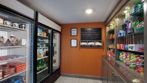 A snack and beverage section with refrigerated and non-refrigerated shelves, a chalkboard sign, and a clean, tiled floor.