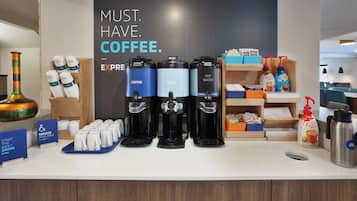 Un espace dédié au café, équipé de plusieurs distributeurs de café, d’une machine à café et d’un panneau indiquant : « IL FAUT ABSOLUMENT DU CAFÉ ».