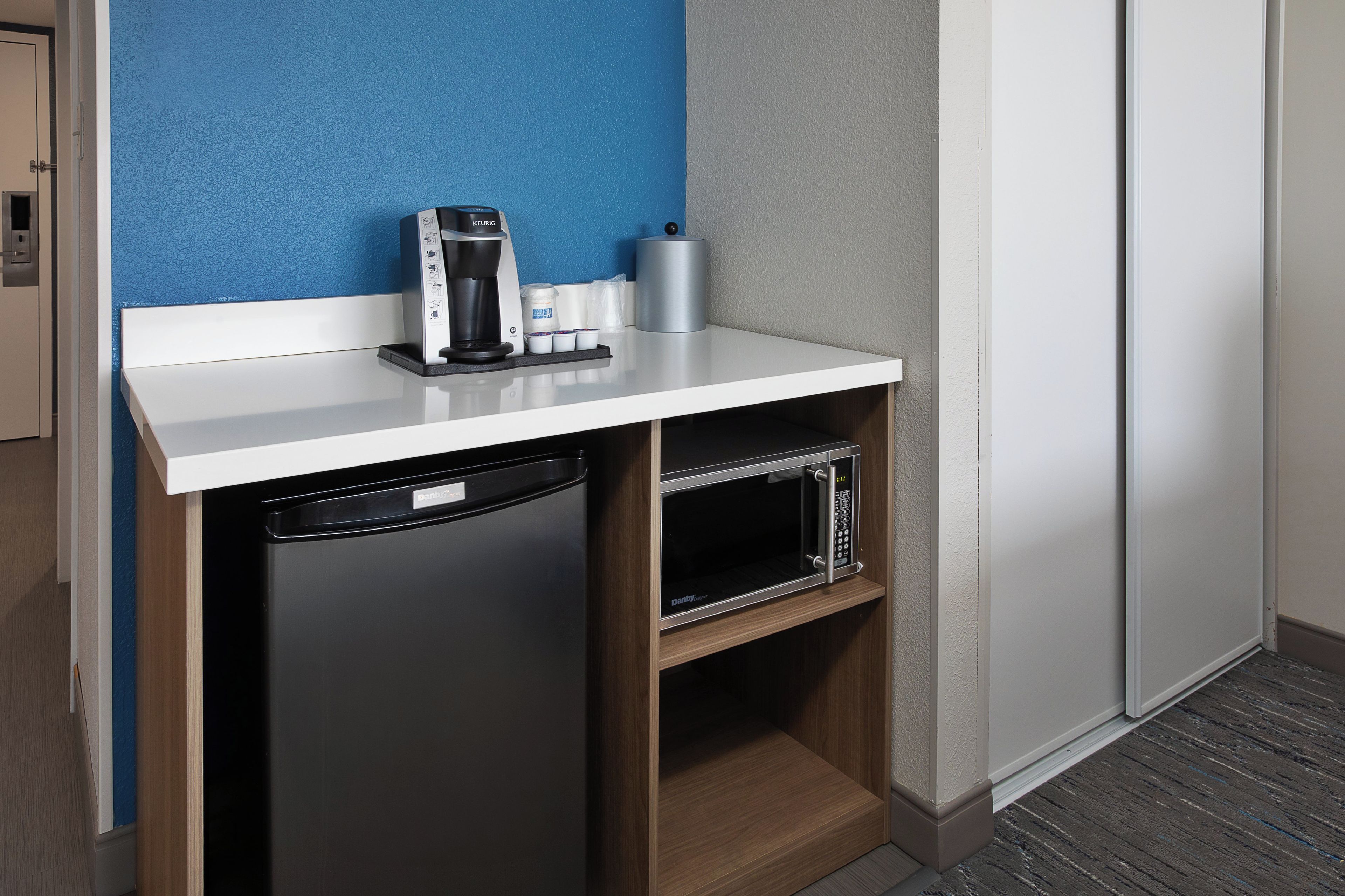 Una kitchenette compacta con cafetera, microondas y lavavajillas.