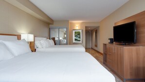 Une chambre d’hôtel avec deux lits, un téléviseur posé sur un meuble en bois et un tableau encadré au mur.