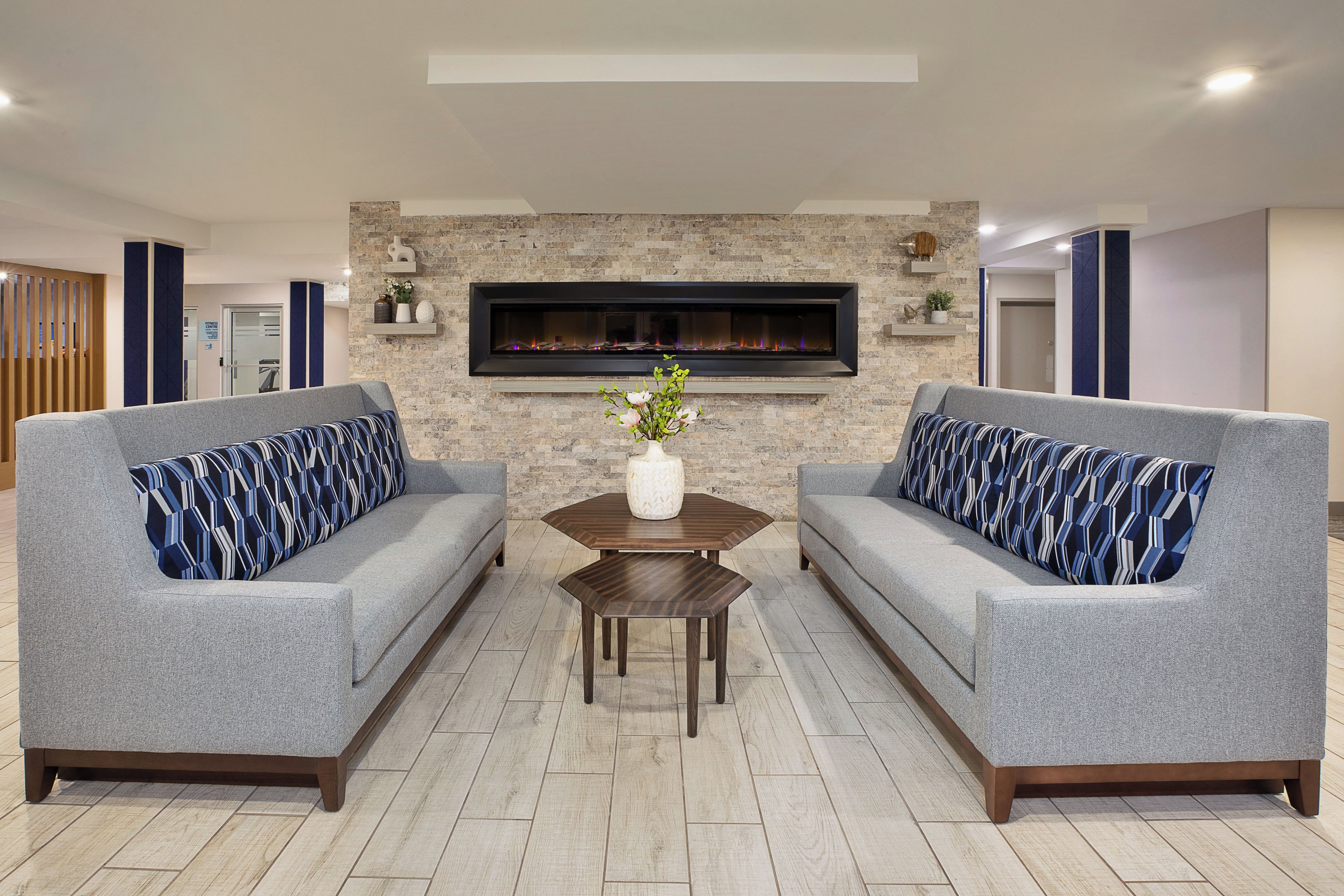 A modern living room with two grey sofas, a wooden coffee table, and a fireplace.