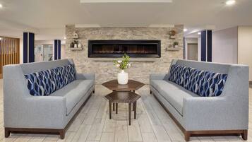 A modern living room with two grey sofas, a wooden coffee table, and a fireplace.