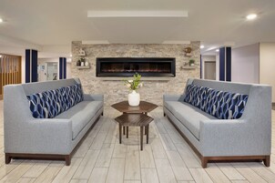 A modern living room with two grey sofas, a wooden coffee table, and a fireplace.